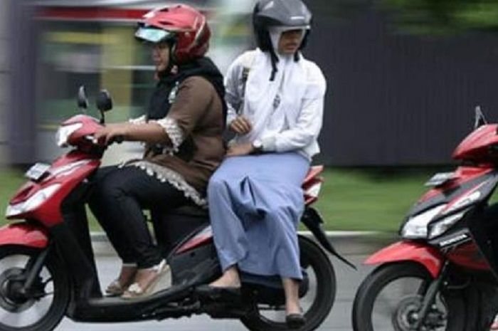 Perempuan pengendara sepeda motor dengan rok panjang